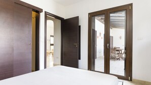 Une chambre dotée d’un grand lit, d’une armoire et d’une porte-fenêtre coulissante donnant sur un balcon avec une table et des chaises.