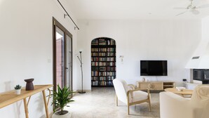 Un salon moderne avec un canapé, un fauteuil et une bibliothèque remplie de livres.
