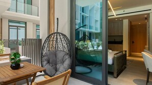 A modern interior with a glass partition, a hanging chair, a bed, and a dining area. - Chic Studio with Pool Access in The Autograph (Dubai)