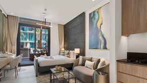 A modern hotel room with a bed, sofa, dining area, and kitchen. - Chic Studio with Pool Access in The Autograph (Dubai)