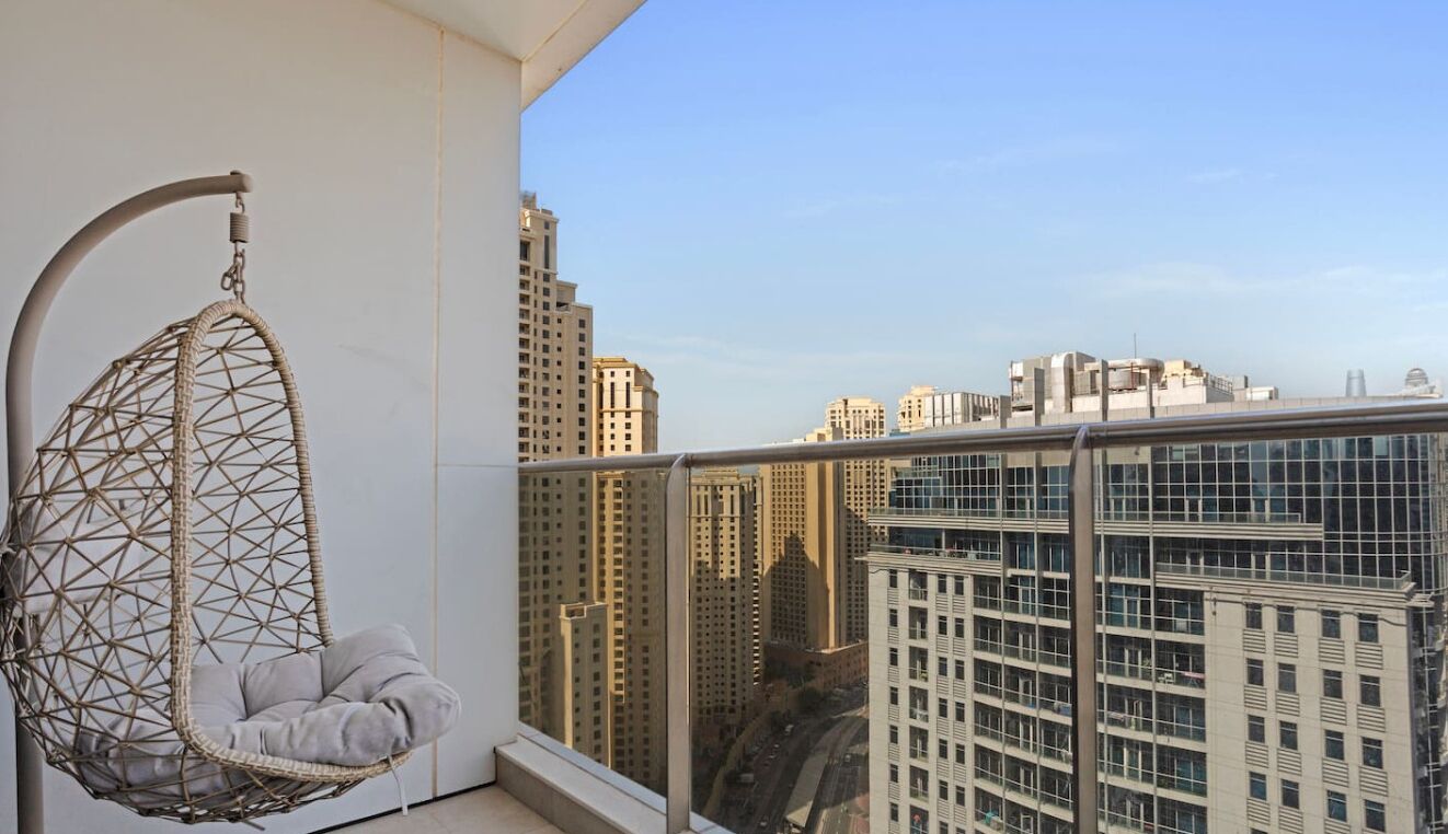 A hanging chair on a balcony with a cityscape view.