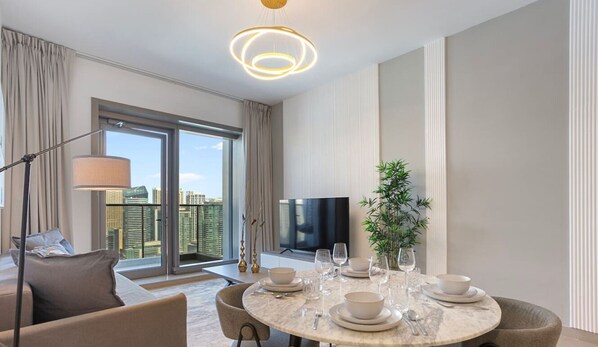 Een moderne hotelkamer met een eethoek, een groot raam met uitzicht over de stad en een flatscreen televisie.