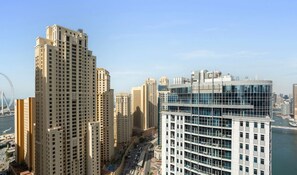 A high-rise building with a modern glass facade, surrounded by other tall buildings and a clear sky.
