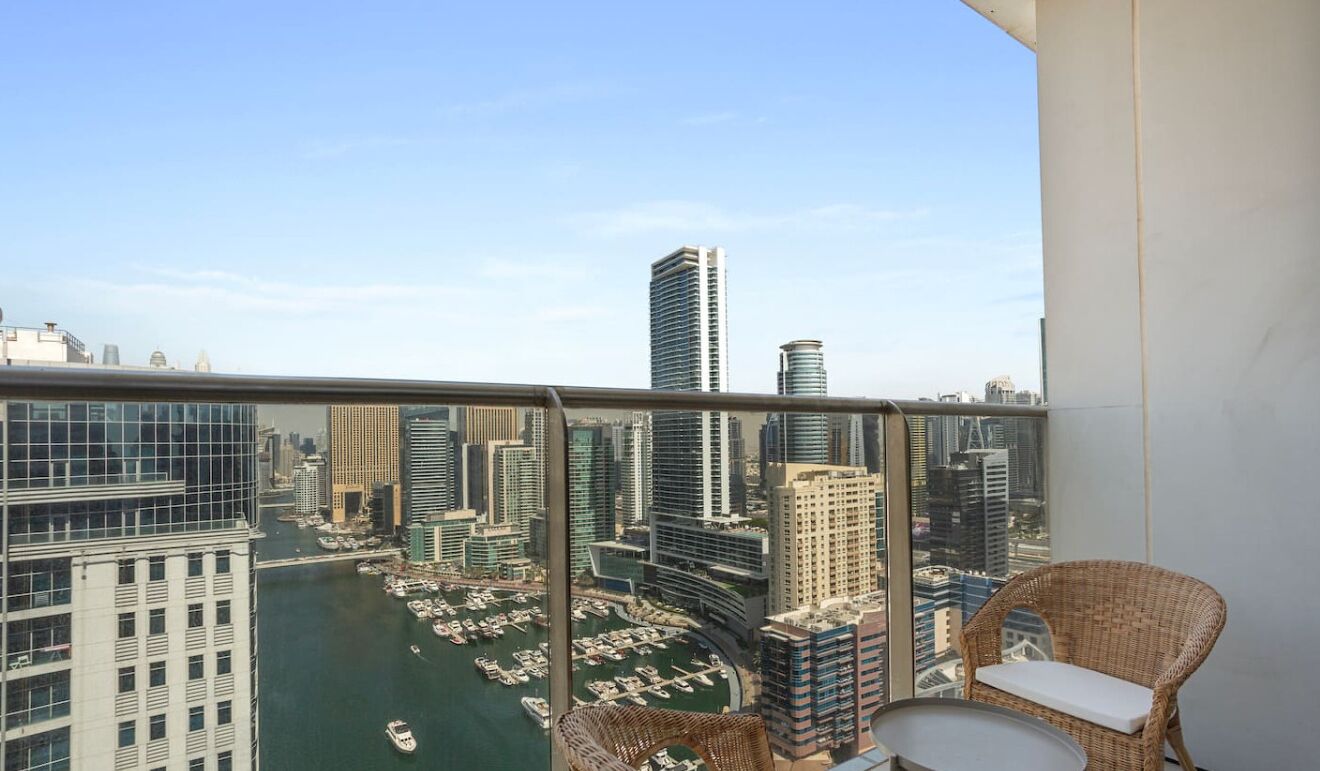 Uma varanda com vista para a paisagem urbana, incluindo edifícios altos e um porto de iates.