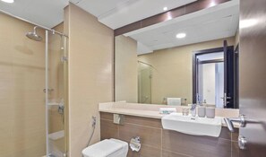 A modern bathroom with a glass shower enclosure, a white toilet, and a vanity with a mirror.