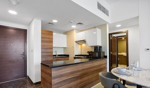 Una cocina moderna con una isla de madera, armarios blancos y un comedor con una mesa de mármol.