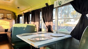 Interior de un café retro con asientos en cabina, una mesa con platos y un letrero que dice 'I ME'.