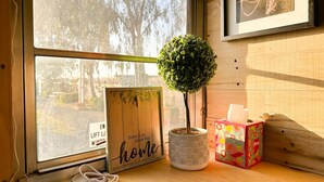 Un escritorio de madera con una planta en maceta, un cartel enmarco y una caja de pañuelos.