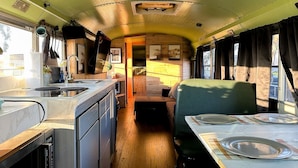 Interior compacto de una caravana con kitchenette, comedor y zona de estar.