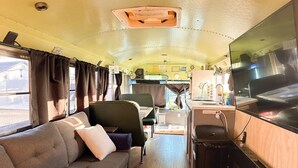 Interior compacto de una caravana con sofá, una pequeña mesa de comedor y una zona de kitchenette.