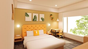 A modern hotel room with a large bed, a small table, and a chair. There are wall-mounted lights, a window with a view of trees, and a wall with framed pictures. - Bloom Hotel - Taloja Navi Mumbai (Panvel)
