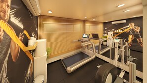 A modern gym with exercise equipment, a treadmill, and a wall-mounted air conditioner. - Bloom Hotel - Taloja Navi Mumbai (Panvel)