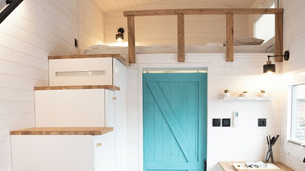 Une cuisine de taille réduite avec des meubles blancs, une porte de couleur turquoise et des plans de travail en bois.