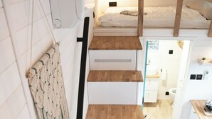 Un escalier menant à une chambre à coucher dotée d’une tête de lit en bois, d’une décoration murale en macramé et offrant une vue sur la salle de bain.