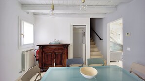 Ein Zimmer mit Glastisch, Holzschrank und einer Treppe zu einer weiteren Ebene.