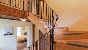 Una escalera de madera con barandales de metal negro que sube a un piso superior.