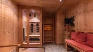 Interior de madera con una sauna, un banco y una cesta de mimbre.