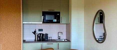 A modern kitchen with a microwave, sink, and a round dining table with four chairs.