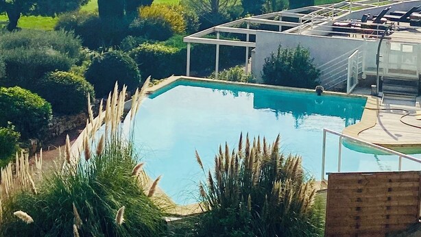 En pool med udsigt over det omkringliggende landskab, herunder træer og et fjernt tårn.