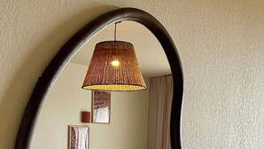 En stue med en sofa, to puder, et rundt træbord og en hængende lampe.