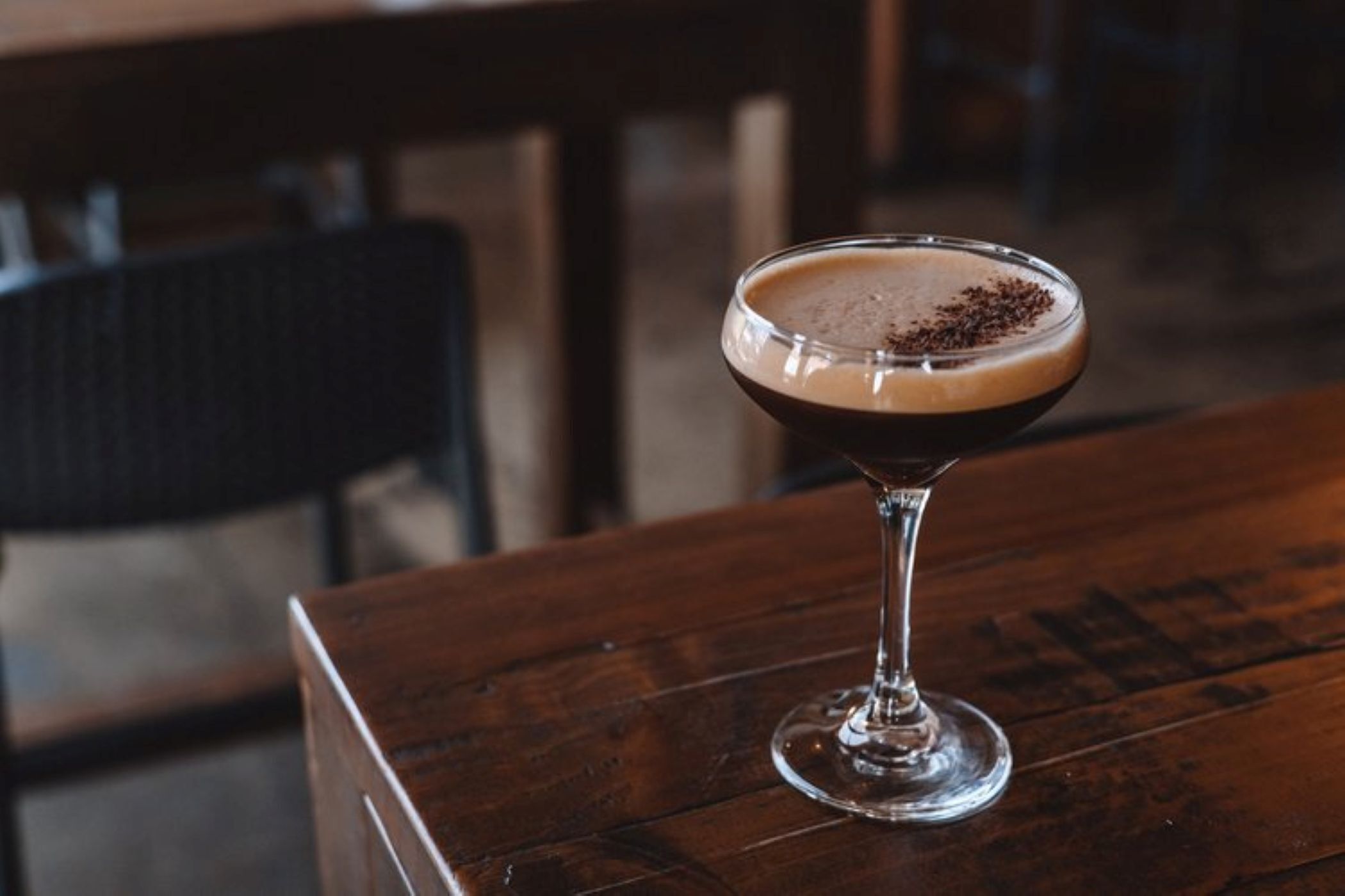 A cocktail in a martini glass on a wooden table.