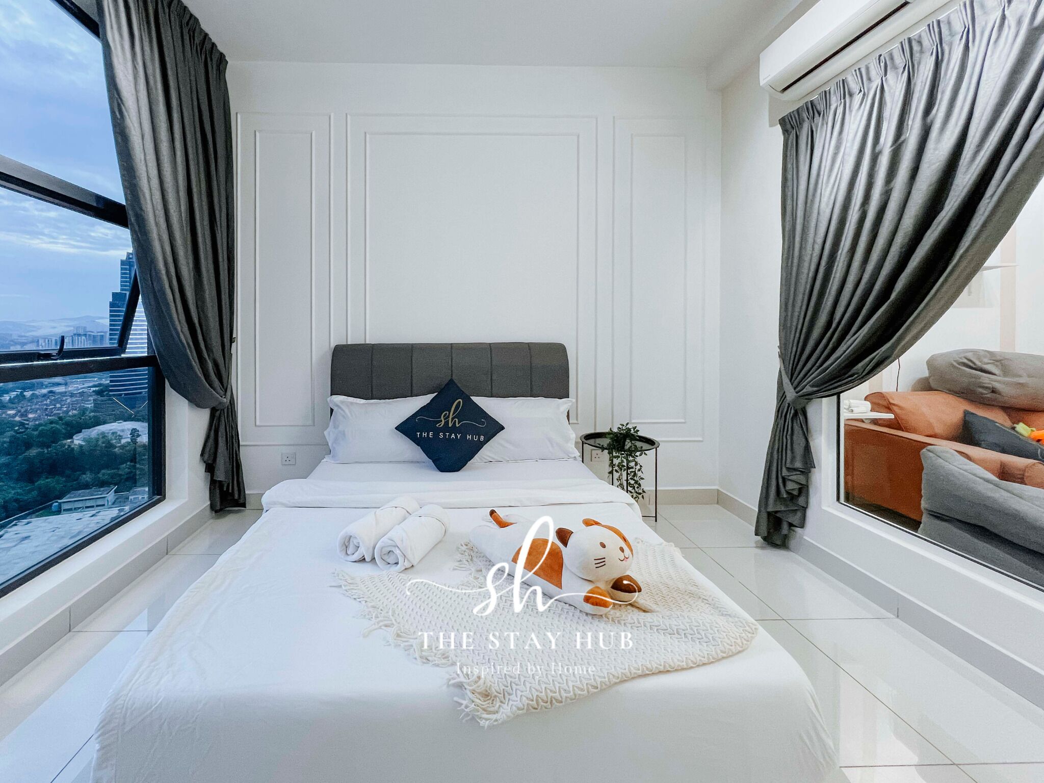 A modern bedroom with a large bed, a view of the city, and a cozy seating area.