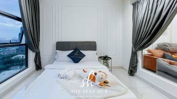 A modern bedroom with a large bed, a view of the city, and a cozy seating area.