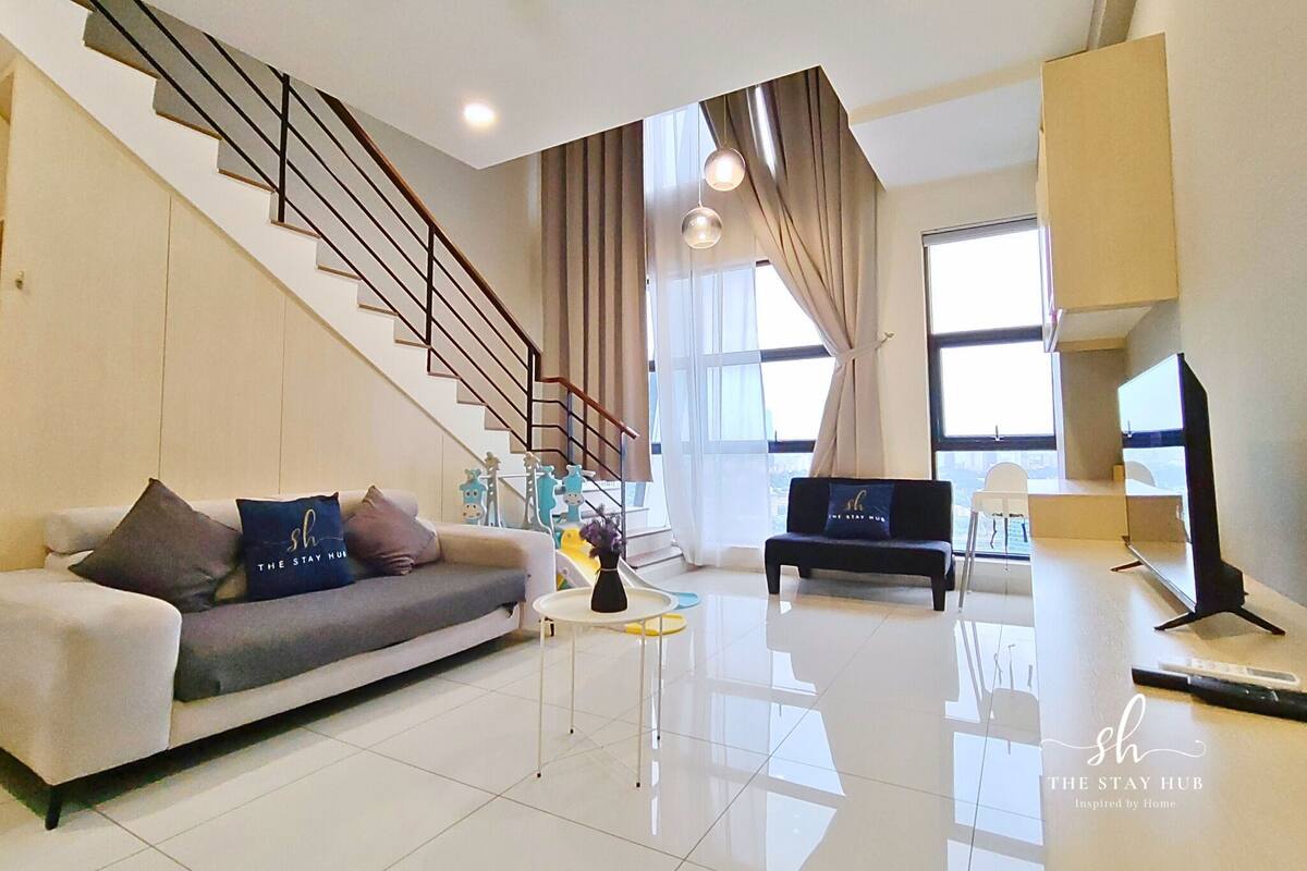 A modern living room with a sofa, a coffee table, a bench, a TV, and a staircase.