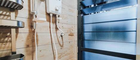 Un baño con pared de madera, ducha integrada y un amplio ventanal con persianas.