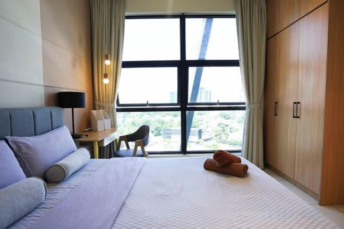 A hotel room with a bed, a desk, a chair, and a wardrobe.