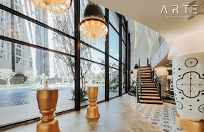 A modern hotel lobby with large windows, a staircase, and a gymnasium area. - Arte Mont Kiara Luxury Suite by Stay Hub (Kuala Lumpur)