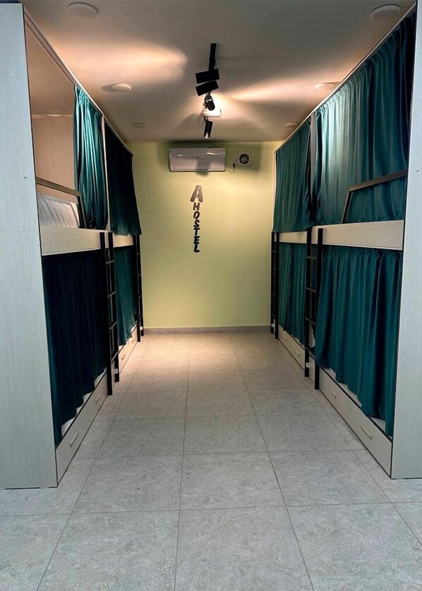 Un couloir avec des lits superposés, un ventilateur de plafond et un appareil de climatisation.