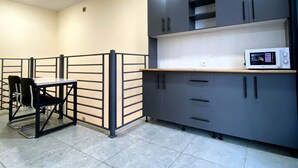 A kitchenette with grey cabinets, a microwave, and a small table with chairs.