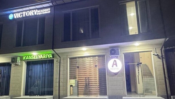 A building with a sign for 'A HOSTEL' at the top. There is a sign for 'VICTORY ACADEMY' and another for 'KANSELYARIYA' below it.
