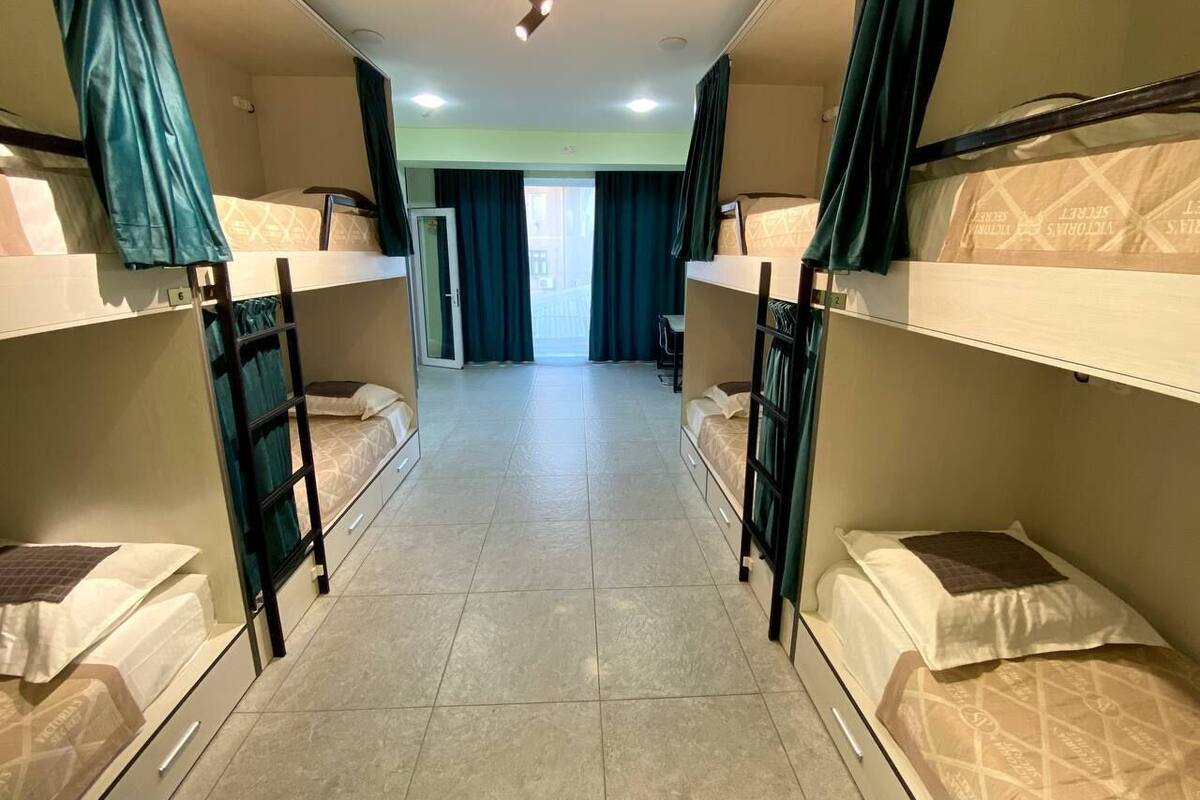 A room with bunk beds, a desk, and a view through a door.
