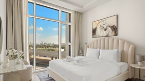 Quarto de hotel moderno com uma cama grande, vista para a cidade e um quadro na parede.