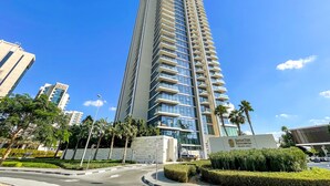 Um edifício alto com design moderno, com várias varandas e fachada de vidro.