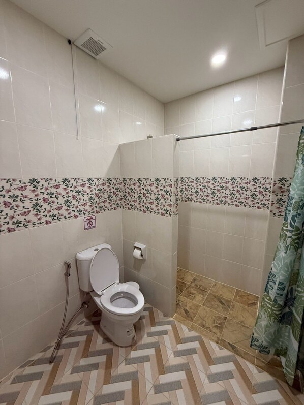 Un baño con inodoro, ducha y paredes con azulejos.