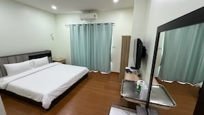 A hotel room with a bed, a TV, a mirror, and a small table with a tray. - The Burapa Rooms (Bangkok)