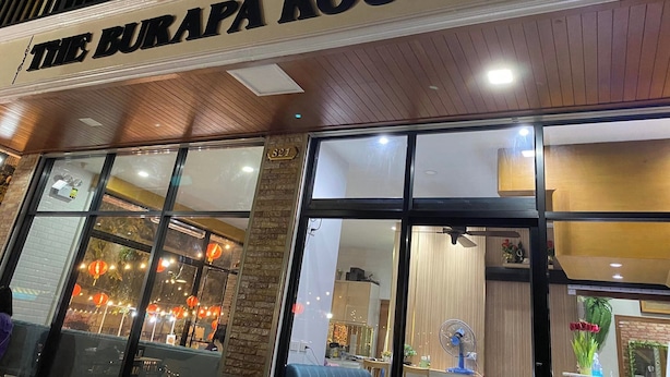 The exterior of The Burapa Rooms with a sign above the entrance, a brick column, and large windows. - The Burapa Rooms (Bangkok)