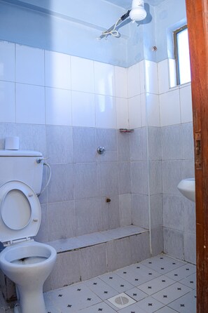 A bathroom with a toilet, shower, and sink. - ORYX HOTELS LIMITED (Nairobi)