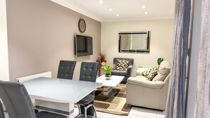 A modern living room with a dining table, two chairs, a sofa, a coffee table, and a TV. - Marylebone Executive Apartments (London)