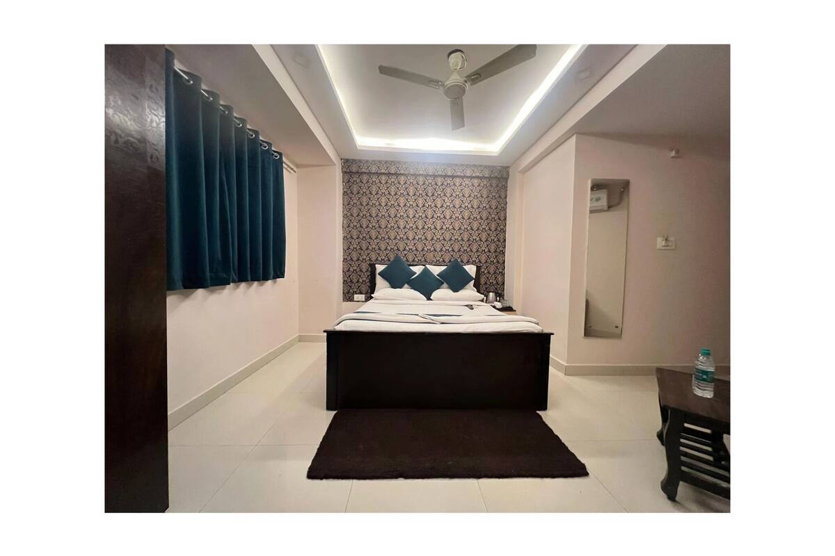 Une chambre à coucher avec un lit, un ventilateur de plafond, une table de chevet et une bouteille d’eau posée sur une table.