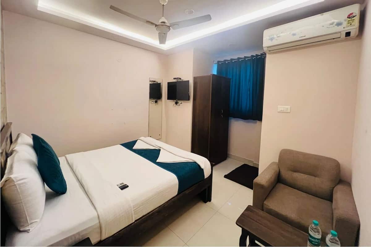 Une chambre d’hôtel équipée d’un lit, d’une chaise, d’un ventilateur de plafond, d’une télévision et d’un appareil de climatisation.