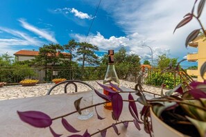 Una terrazza con un tavolo, una bottiglia e piante in vaso.