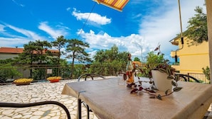 Eine Terrasse im Freien mit einem Tisch, Stühlen und einem gestreiften Sonnenschirm.