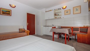 Ein kleines Zimmer mit einem Bett, einem Esstisch und einer Bank.
