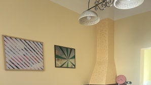 Un comedor con una mesa y sillas de madera, una lámpara decorativa en el techo y dos obras de arte colgadas en la pared.