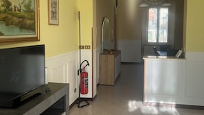 Un salón amplio con televisor, extintor y un cuadro en la pared.
