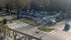 Un estacionamiento con coches, un paso de cebra y una calle con semáforos.